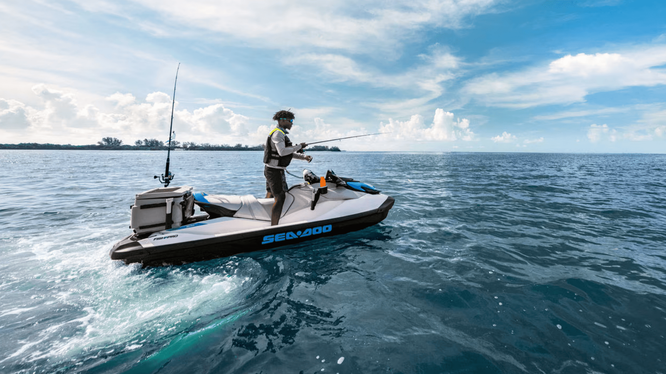 Man fishing on a 2025 Sea-Doo FishPro™ Scout personal watercraft equipped with gear and rod holders in open ocean under a blue sky.