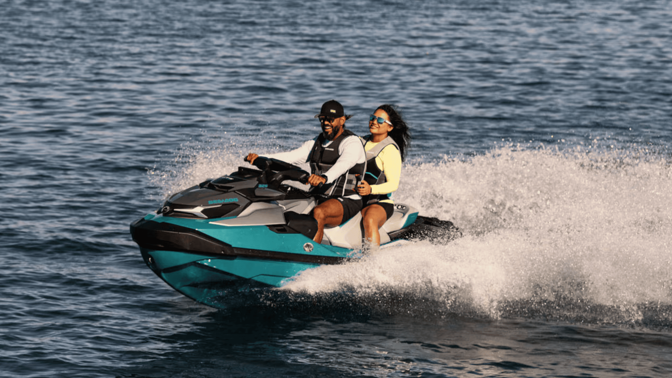 Couple riding the 2025 Sea-Doo GTX™ Limited personal watercraft at speed across open water.